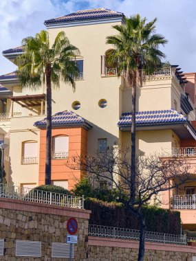 Benalmadena, İspanya - 24 Aralık 2025: Benalmadena Costa del Sol İspanya 'da palmiye ağaçlı konut mimarisi Akdeniz tarzı binalar ve parlak bir yeşillik altında sergileniyor.