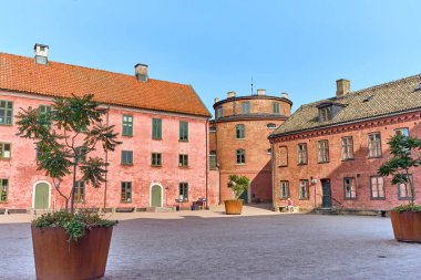 Landskrona, İsveç - 8 Ağustos 2025: Citadel avlusu İsveç 'te tarihi bir dönüm noktasını temsil eden açık mavi gökyüzü altındaki kırmızı tuğla binaları ve yuvarlak kuleyi sergiliyor.