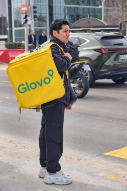 Madrid, İspanya - 5 Mart 2026: Konser ekonomisi ve gıda dağıtım hizmetleri, modern kentsel yaşam tarzını temsil eden San Christobal Madrid İspanya 'da bekleyen Glovo kuryesini gösteriyor.