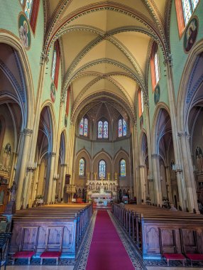 Budapeşte, Macaristan, 1 Mayıs 2025. Yeni-Roma kilisesinin içinde yüksek tavanlı kırmızı halı koridoru ve renkli vitraylı Budapeşte Macaristan pencereleri var. Yüksek kalite fotoğraf.