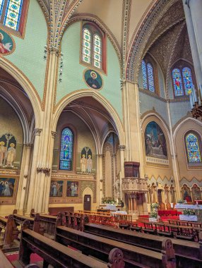 Budapeşte, Macaristan, 1 Mayıs 2025. Budapeşte Macaristan 'da kemerli tavanlar, ahşap sıralar ve canlı vitraylı camlarla kaplı katedral içi. Yüksek kalite fotoğraf.