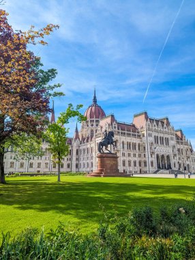 Budapeşte, Macaristan, 1 Mayıs 2025. Budapeşte Macaristan hükümetinde neo-gotik mimarisi ve yeşil çimenliği olan Macar parlamento binası. Yüksek kalite fotoğraf.