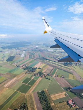 Varşova, Polonya, Mayıs 01, 2025. Uçak kanadı kırsal tarım arazisi üzerinde uçarken yama alanları geometrik modeller ve uçuş sırasında çeşitli araziler havadan seyahat perspektifini gösteriyor. Yüksek kalite fotoğraf