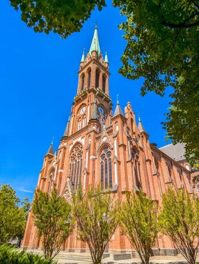 Varşova, Polonya, Mayıs 01, 2025. Varşova Polonya 'da yüksek kule süslemeleri ve kırmızı tuğla cepheleriyle muhteşem bir neo-gotik katedral dış görünüşü var. Mavi gökyüzüne karşı etkileyici bir dini mimari eser sergiliyor. Yüksek kalite fotoğraf