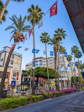 Antalya, Türkiye, 20 Temmuz 2025, Antalya Türkiye 'de ikonik Akdeniz sokak manzarası yaratan yüksek palmiye ağaçlarıyla dolu bulvarın üzerinde Türk bayrağı dalgalanmaktadır. Yüksek kalite fotoğraf