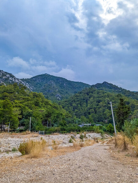 Rural Mediterranean landscape with mountains rising beyond flat terrain under dramatic cloudy sky near Antalya Turkey. High quality photograph