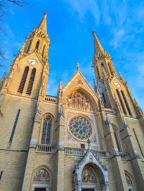 Budapeşte, Macaristan, 1 Mayıs 2025. Budapeşte Macaristan katedralindeki süslü portallı ve gül rengi pencereli çift sarmallı gotik kilise cephesi. Yüksek kalite fotoğraf.