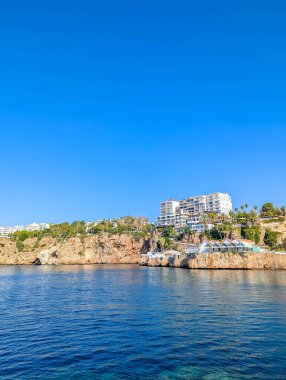 Pristine turquoise Mediterranean waters meet rocky coastline under brilliant blue sky creating stunning seascape near Antalya Turkey. High quality photograph