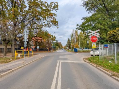 Varşova, Polonya, 20 Ekim 2025. Warszawska Kolej Dojazdowa WKD istasyonu Polonya 'da kırmızı trafik ışığı ve sonbahar ağaçlarıyla demiryolu geçidi. Yüksek kalite fotoğraf