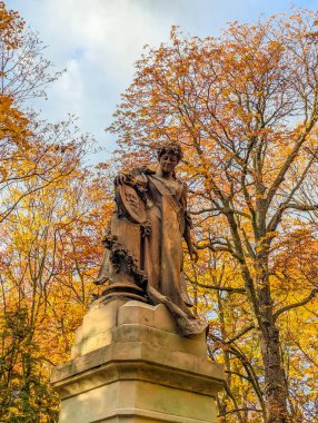 Varşova, Polonya, Mayıs 01, 2025. Polonya 'nın Varşova kentindeki Powzki Mezarlığı' nda sonbahar ağacı altında yaprakları dökülen tarihi mezarlık anıtı. Yüksek kalite fotoğraf.