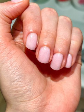 Plock Polonya 'daki doğal deri dokusuna karşı soluk pembe manikürlü ve gümüş yüzüklü kadın elinin detaylarını kapat. Yüksek kalite fotoğraf.