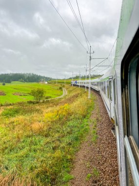 Leba, Polonya, 19 Temmuz 2025, Zakopane Polonya 'nın kırsal kesimindeki Tatra bölgesi manzaralı fırtınalı gökyüzü altında yeşil vadi kırsalında uzanan dağ demiryolu hattı. Yüksek kalite fotoğraf.