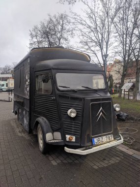 Vilnius, Litvanya, Mayıs 01, 2025. Litvanya 'nın Vilnius kentindeki çıplak kış ağaçlarının altına park edilmiş klasik siyah Citroen H Van vintage yemek kamyonu. Yüksek kalite fotoğraf.