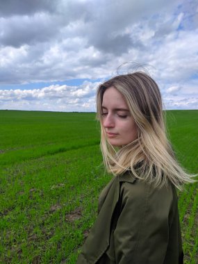 Brest, Belarus, 1 Mayıs 2025. Zeytin rengi ceketli genç bir kadın huş ağacının gövdesine nazikçe poz vererek doğal bir portre kompozisyonu oluşturuyor. Yüksek kalite fotoğraf