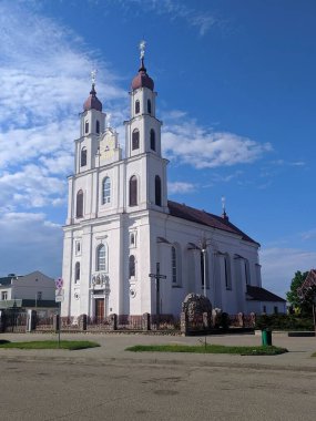 Dyatlovo, Belarus, 1 Mayıs 2025. Beyaz barok Katolik kilisesi, ikiz çan kuleleri ve klasik cepheleri mavi bulutlu bahar gökyüzüne karşı görkemli bir şekilde duruyor. Yüksek kalite fotoğraf