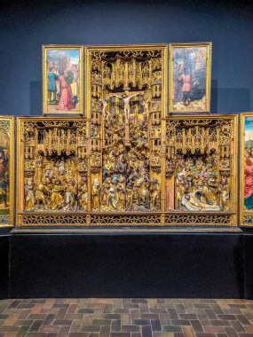 Warsaw, Poland, May 01, 2025. Gothic carved wooden triptych altarpiece with ornate golden details and religious narrative scenes displayed at National Museum medieval art exhibition. High quality photograph
