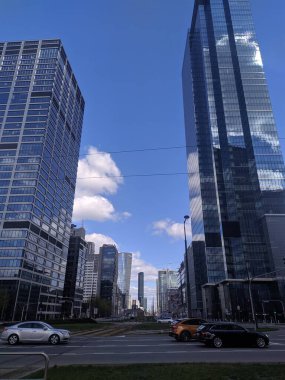 Warsaw, Poland, May 01, 2025. Contemporary high-rise office buildings and skyscrapers with glass facades forming urban canyon in Warsaw business center under cloudy sky. High quality photograph