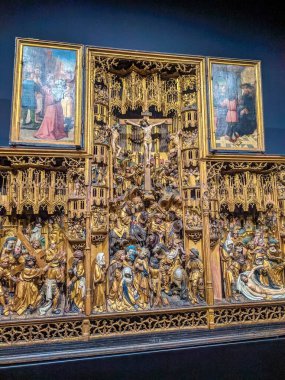 Warsaw, Poland, May 01, 2025. Large medieval golden altarpiece triptych with detailed religious scenes displayed behind protective glass at National Museum Warsaw. High quality photograph
