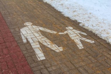 Varşova, Polonya, Ocak 01, 2025. Beyaz boyanmış aile yaya geçidi sembolleri yetişkinleri ve çocuğu kırmızı tuğlalı kaldırımda gösteriyor. Yüksek kalite fotoğraf.