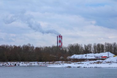 Varşova, Polonya, Ocak 01, 2025. Karlı kıyıları ve bulutlu kış gökyüzü ile donmuş Vistula Nehri 'nin üzerindeki uzak köprü manzarası. Yüksek kalite fotoğraf