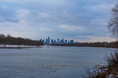 Varşova, Polonya, Ocak 01, 2025. Varşova şehir merkezindeki gökdelenler kış mevsiminde kısmen donmuş Vistula Nehri kıyılarının ötesinde görülebiliyor. Yüksek kalite fotoğraf