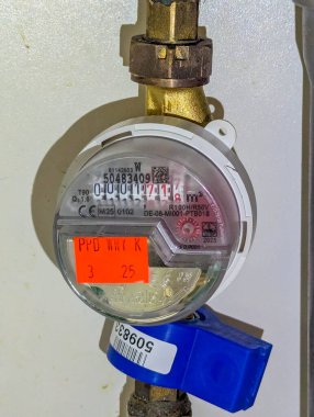 Varşova, Polonya, Mayıs 01, 2025. Bakır bir borunun üzerinde mavi saplı bir su sayacının yakın çekimi. Yüksek kalite fotoğraf.