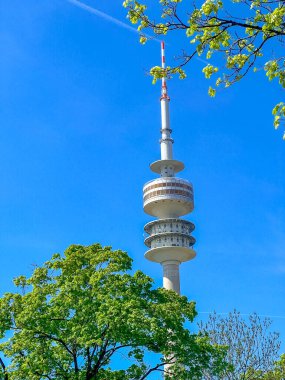 Varşova, Polonya, Mayıs 01, 2025. Iconic Varşova Radyo Mast Kulesi ilkbaharda açık mavi gökyüzüne karşı yemyeşil ağaçların arasında dimdik ayakta duruyor. Yüksek kalite fotoğraf