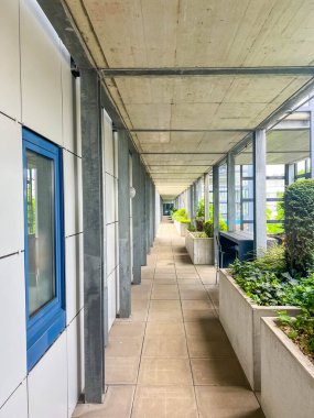 Varşova, Polonya, Mayıs 01, 2025. Beton tavanlı, bej duvarlı, mavi kapılı modern minimalist koridor kurumsal yapıda perspektif yaratıyor. Yüksek kalite fotoğraf