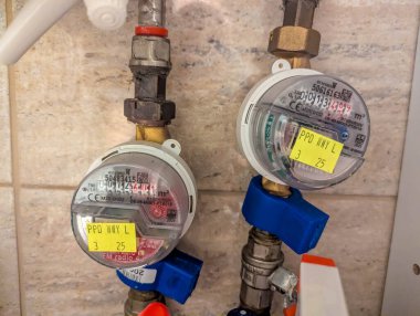 Varşova, Polonya, Mayıs 01, 2025. Boruları ve mavi valfleri olan iki su metresi kış parkı malzeme odasındaki fayanslı bir duvara dayanıyor. Yüksek kalite fotoğraf.