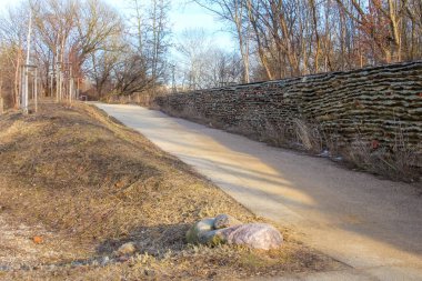 Varşova, Polonya, Mart 01, 2026. Çimenli tepeler ve taş desenli duvarlar arasında kıvrımlı bir çakıl yolu var. Yüksek kalite fotoğraf.