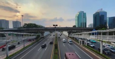 Jakarta, Endonezya 30 Temmuz 2025: Jakartas iş bölgesinde modern gökdelenlerle çevrili çok şeritli bir otoyolda trafik manzarası.