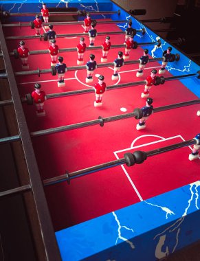 Kırmızı ve mavi üniformalı minyatür futbolcuların oynadığı renkli bir langırt masası..