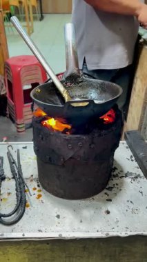 Bogor, Endonezya - 17 Ekim 2025: Endonezya 'da kömür ocağı üzerinde ızgara tavasında geleneksel Endonezya usulü kızartılmış köri yemeği yapan bir sokak yemeği satıcısı..