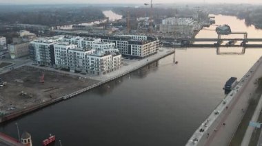 Polonya, Szczecin 'in panoramik hava manzarası, gün batımında. Görüntü, köprüden ve rıhtım boyunca ilerleyen trafik ile hareketli şehir yaşamını yakalıyor. Yeni mimari gibi modern mimarinin dinamik karışımını sergiliyor.