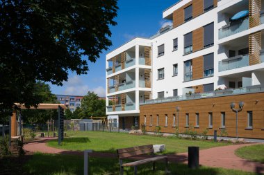 Güzel peyzajlı iç avlusu olan modern bir apartman dairesi. Bahçede yemyeşil bir çimen, bir yürüyüş yolu ve sakinlerin dinlenmesi için bankları olan ahşap bir pergola bulunuyor. Binanın çağdaş bir tasarımı var.