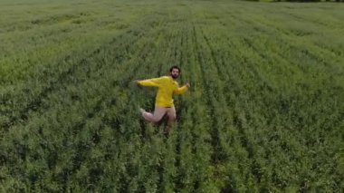 Bir adam hip hop yapıyor ve yeşil bir tarlanın ortasında kameraya bakıyor.