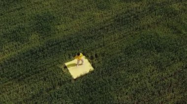 Ağır çekim. Yeşil bir tarlanın ortasında bir adam dans ediyor. Ekilmiş buğday tarlasının genel planı
