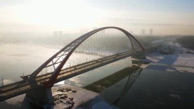 Bugrinsky köprüsüne karşı batan güneş ve aydınlık sis. Kışın Novosibirsk Köprüsü. hava 4k
