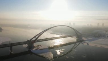 Kış nehri üzerindeki büyük bir köprünün havadan çekilmiş görüntüleri. Novosibirsk 'teki Bugrinsky Köprüsü 4k