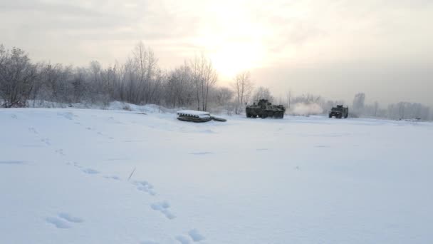 ロシアのノヴォシビルスク – 2020年11月18日:日の出を背景に雪の多い冬の道を軍用輸送車が走る — ストック動画