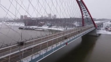 Novosibirsk 'teki Bugrinsky Köprüsü' nde aşırı hız. Kırmızı yol köprüsünün üzerinden uçuyor. Otoyol ve nehrin kış manzarası