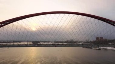 4K 'da hava fotoğrafçılığı. Gri gökyüzü ve güneşin arkaplanındaki köprünün silueti