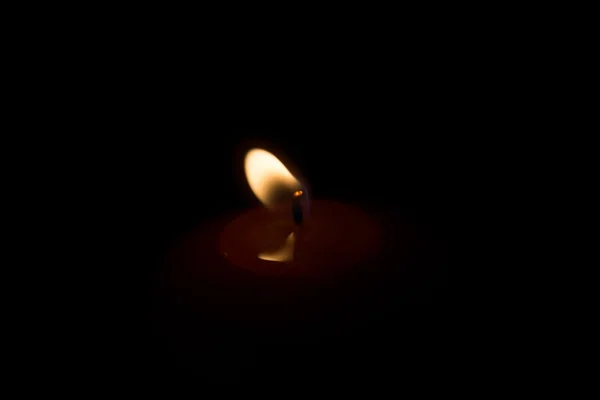 The dim light of a candle in the room
