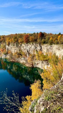 Zalew Zakrzowek, Krakow, Polonya. Açık mavi bir gökyüzünün altında açık kireçtaşı uçurumlarının ve renkli sonbahar ormanlarının ayna yansıması olan derin mavi göl güneşli bir günde.