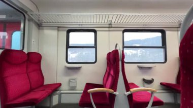 Hareket eden bir Polonyalı tren vagonunda çekilmiş yatay video, dışarıda karlı bir kış manzarası olan boş kırmızı koltuklar ve pencereleri gösteriyor. Polonya demiryolu, Polonya. Seyahat, ulaşım teması