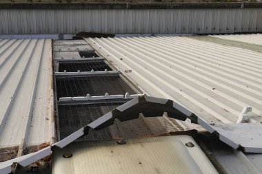 Damaged metal roof of an industrial building. Repair of broken panels. Roofing material.