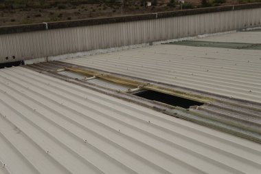 Damaged metal roof of an industrial building. Repair of broken panels. Roofing material.