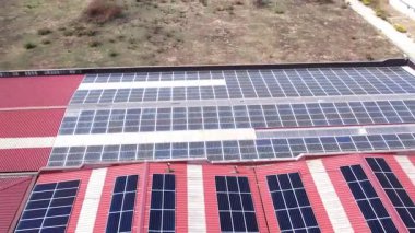 İnsansız hava aracı bir sanayi bölgesindeki bir deponun çatısındaki güneş panellerini gösteriyor. Çatıda güneş panelleri olan bir depo..