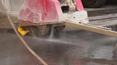 Endüstriyel elmas zemin testeresiyle beton kesmek. İnşaat alanında ıslak beton kesen endüstriyel beton testeresinin yakın çekimi. Elmas bıçak suyla soğutulmuş..