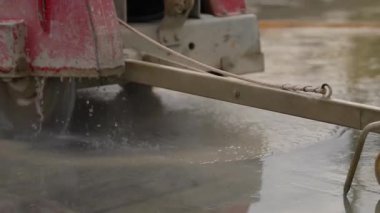 Endüstriyel elmas zemin testeresiyle beton kesmek. İnşaat alanında ıslak beton kesen endüstriyel beton testeresinin yakın çekimi. Elmas bıçak suyla soğutulmuş..